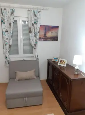 a room with a chair and a desk with a lamp at Apartman Paris in Podgorica