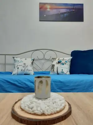 a bedroom with a bed with a blue blanket and a table at Apartman Paris in Podgorica