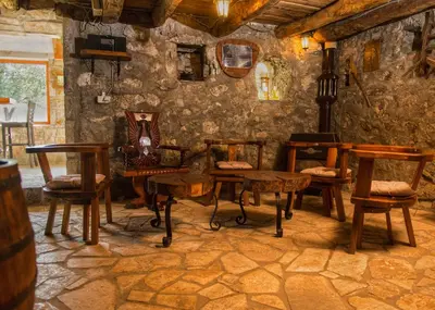 a room with tables and chairs in a stone wall at Konoba Stanisic in Balabani