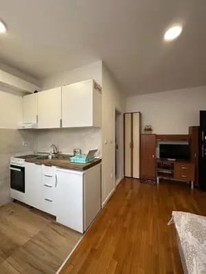 a kitchen with white cabinets and a wooden floor at Stex Urban 2 in Podgorica
