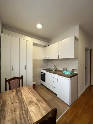 a kitchen with white cabinets and a wooden table at Stex Urban 2 in Podgorica