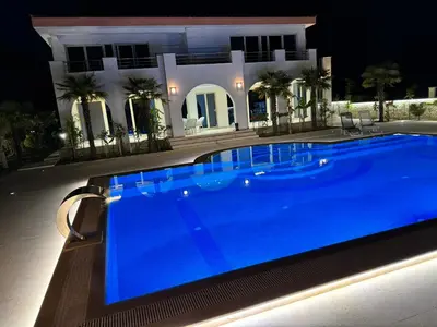 a swimming pool in front of a house at night at Villa 100 Palme in Ulcinj