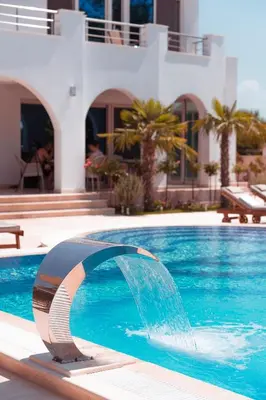 a pool with a water fountain in front of a house at Villa 100 Palme in Ulcinj