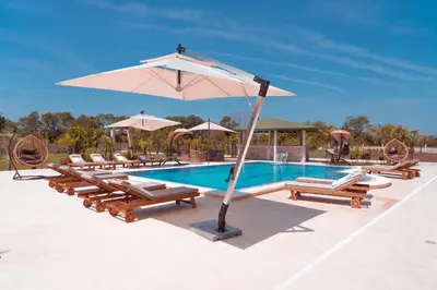 a pool with lounge chairs and an umbrella at Villa 100 Palme in Ulcinj