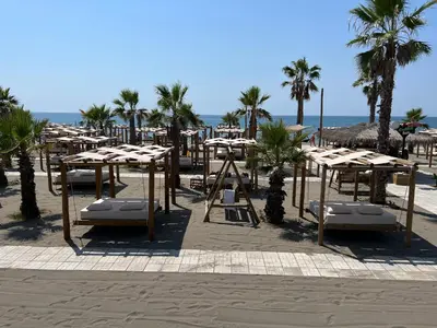 a group of tables and chairs on the beach at Villa 100 Palme in Ulcinj