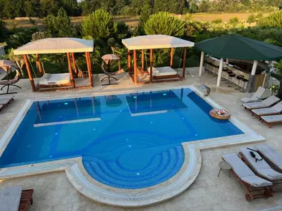 an infinity pool with chairs and a gazebo at Villa 100 Palme in Ulcinj