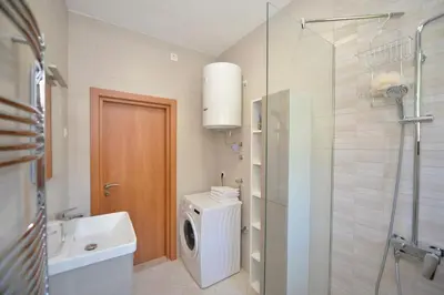 a bathroom with a washing machine and a glass shower at Fjordfront Aerie in Kotor