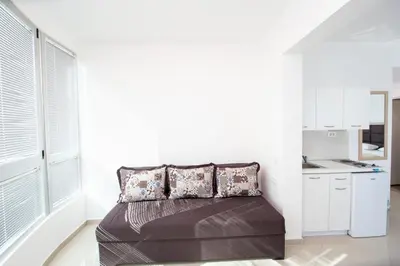 a bedroom with a bed with pillows and a kitchen at Apartments Blanco in Budva
