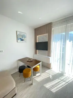 a living room with a table and chairs and a television at Becici - apartment Majestic in Budva