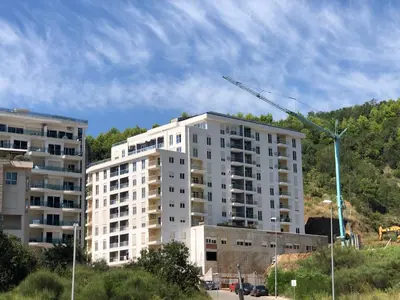 a tall white apartment building with a crane at Becici - apartment Majestic in Budva