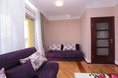 a living room with a purple couch and a window at Apartments Aleksandra in Podgorica