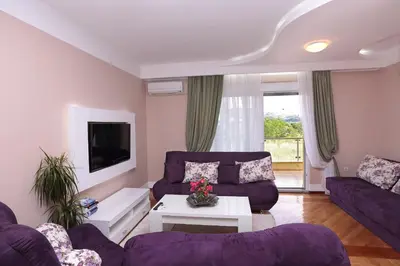 a living room with purple couches and a tv at Apartments Aleksandra in Podgorica