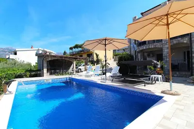 a large blue swimming pool with umbrellas next to a house at 2bd Apt w Private Pool and City View 