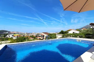 a large blue swimming pool with an umbrella at 2bd Apt w Private Pool and City View 