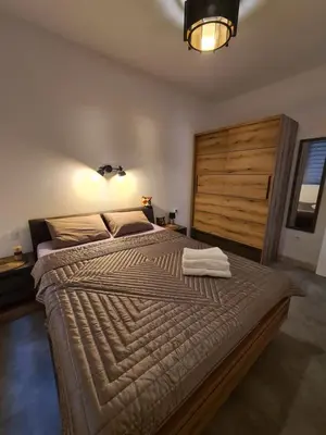 a bedroom with a large bed with a wooden headboard at Черногория Квартира у моря in Rafailovici