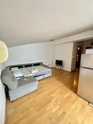 a room with a bed and a couch and a refrigerator at Stex Urban 3 in Podgorica