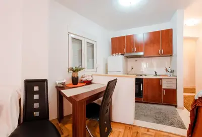 a kitchen with a wooden table and a dining room at Studio Slavica in Budva