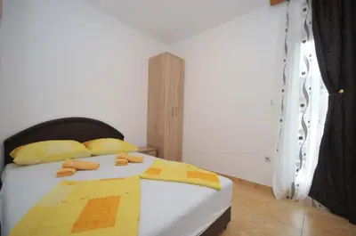 a bedroom with a bed with yellow and yellow pillows at Apartments Nedovic-Jaz in Budva