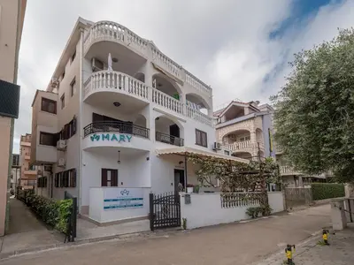 a white building with a balcony on a street at Apartments Mary in Budva