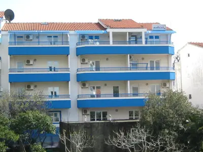 an apartment building with blue balconies and trees at Blue Palace Guest House in Budva