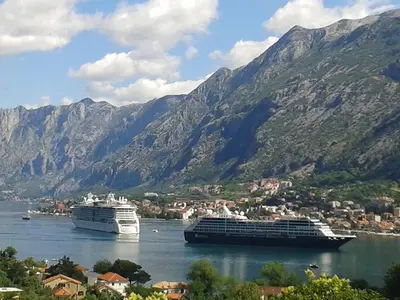 two cruise ships in the water with mountains in the background at Apartments Krivokapic in Kotor