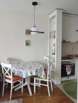 a white kitchen with a table and chairs and a stove at CITY POINT Apartment in Podgorica