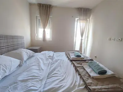 a bed with white sheets and two towels on it at CITY POINT Apartment in Podgorica