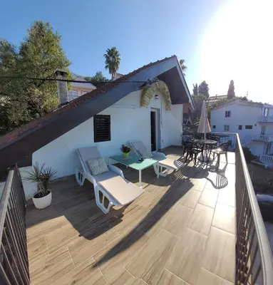 a patio with a table and chairs on a deck at Apartment Old Olive in Dobra Voda