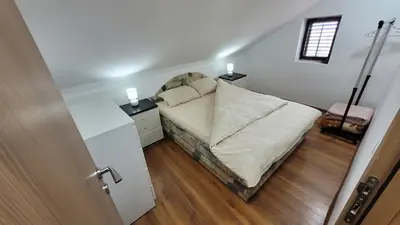 a bedroom with a bed and two night stands and a door at Apartment Old Olive in Dobra Voda