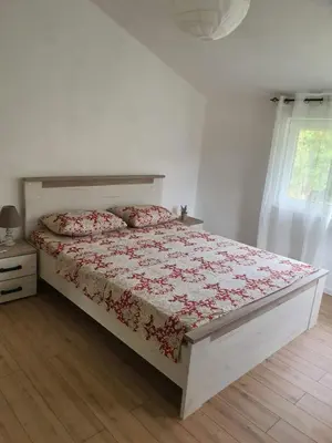 a bedroom with a bed with a red comforter and a window at Sunny Valley in Bar
