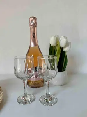 a bottle of wine next to two glasses and flowers at Central Park Apartment in Podgorica