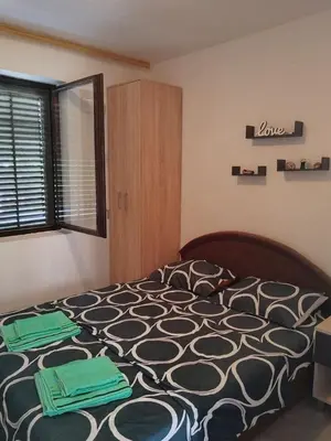 a bedroom with a bed with green towels on it at Apartman Marinamar in Utjeha