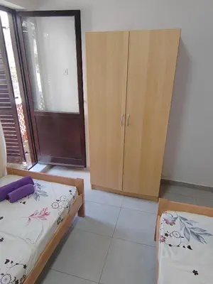 a bedroom with two beds and a cabinet in it at Apartman Marinamar in Utjeha