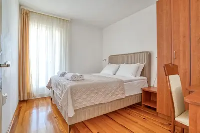 a bedroom with a bed with white sheets and a window at Guesthouse Drašković in Petrovac na Moru