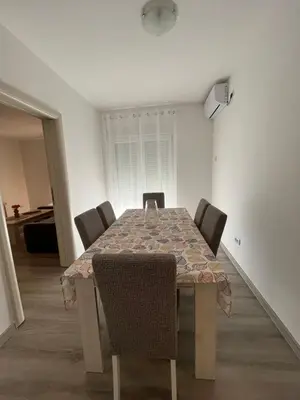a dining room table with chairs in a white room at Orlando apartman in Kotor