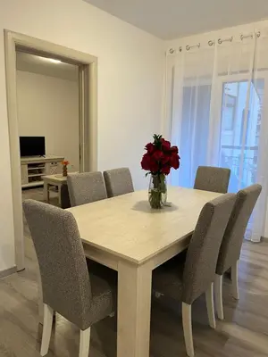 a dining room table with chairs and a vase of red flowers at Orlando apartman in Kotor