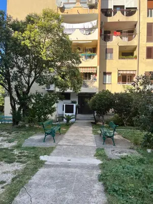 two green benches in front of a building at Orlando apartman in Kotor