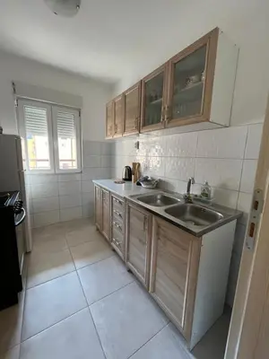 a kitchen with wooden cabinets and a sink at Orlando apartman in Kotor