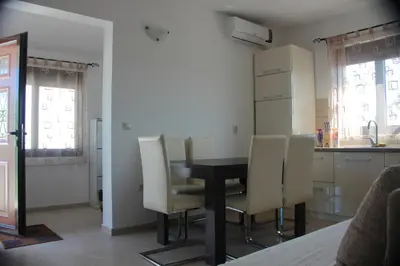 a dining room table with chairs and a kitchen at Apartments Aneta in Ulcinj
