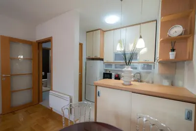 a kitchen with a sink and a counter with chairs at City Nest apartment in Podgorica