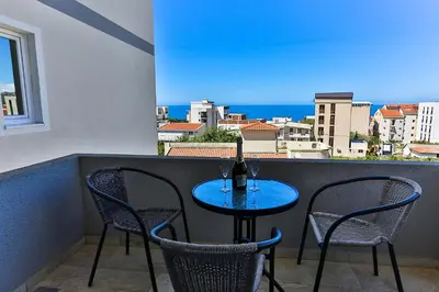 a table with two chairs and a bottle of wine on a balcony at Apartmani BLUE MOON in Dobra Voda