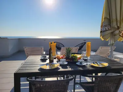 a dining room table with chairs and an umbrella at Apartmani BLUE MOON in Dobra Voda