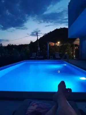 a man laying in a swimming pool at night at lux apartmani Porte Nouva in Sutomore