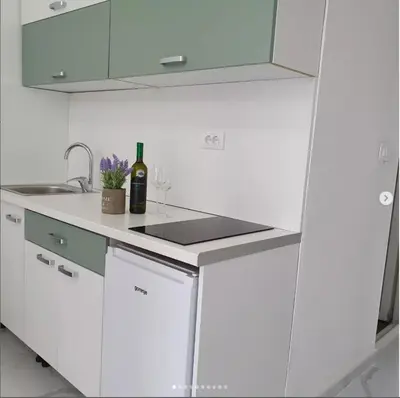 a white kitchen with a sink and a bottle of wine at lux apartmani Porte Nouva in Sutomore