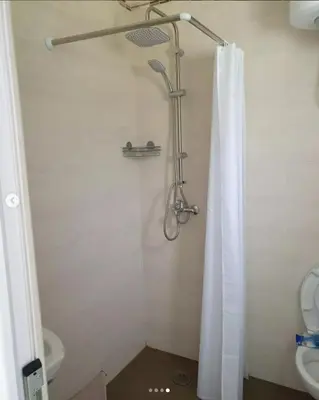 a bathroom with a shower with a curtain and a toilet at lux apartmani Porte Nouva in Sutomore