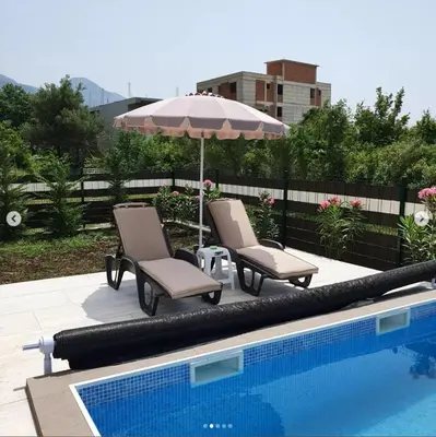two chairs and an umbrella next to a swimming pool at lux apartmani Porte Nouva in Sutomore