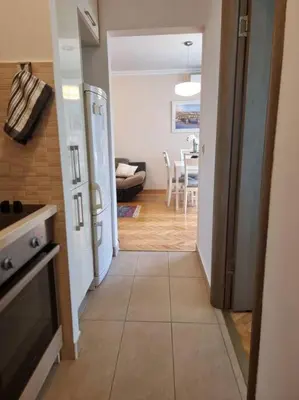 a kitchen with a white refrigerator and a dining room at Cozy Central Apartment next to Bus and Train Station in Podgorica