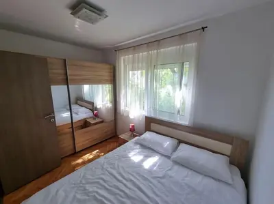 a bedroom with a white bed and a window at Cozy Central Apartment next to Bus and Train Station in Podgorica