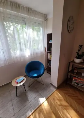 a living room with a blue chair and a table at Cozy Central Apartment next to Bus and Train Station in Podgorica