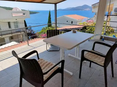 a table and chairs on a balcony with a view of the ocean at 1-Bedroom Apartment in Bigovo